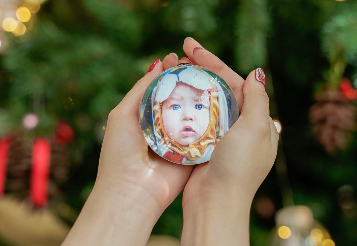 Hands holding a HEARTSPHERE orb with a baby portrait